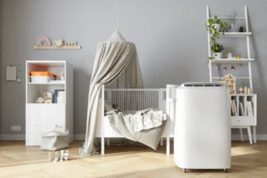 White portable air purifier standing next to a white crib with canopy in a clean, modern baby nursery room