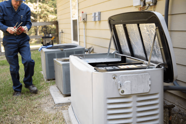 Technician holding tools while walking past a row of outdoor air conditioning and generator units along the side of a house.